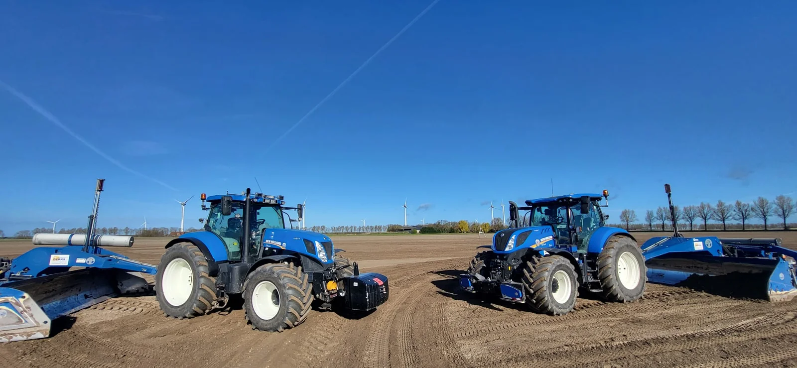 Twee New Holland-tractoren met kilverbakken op een perceel