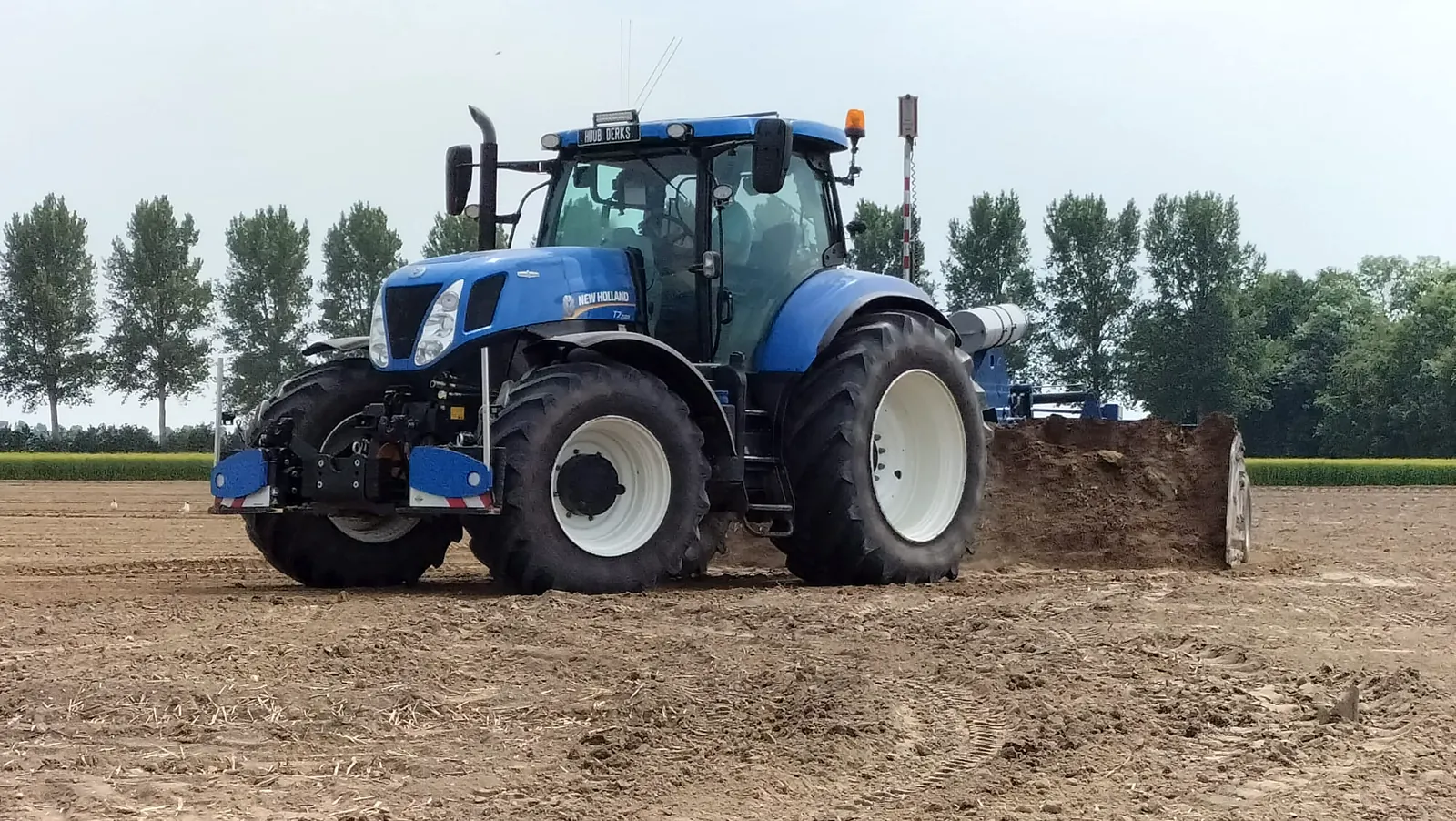 New Holland trekker met AP kilverbak aan het werk op een perceel bij Creil, met een rij populieren op de achtergrond