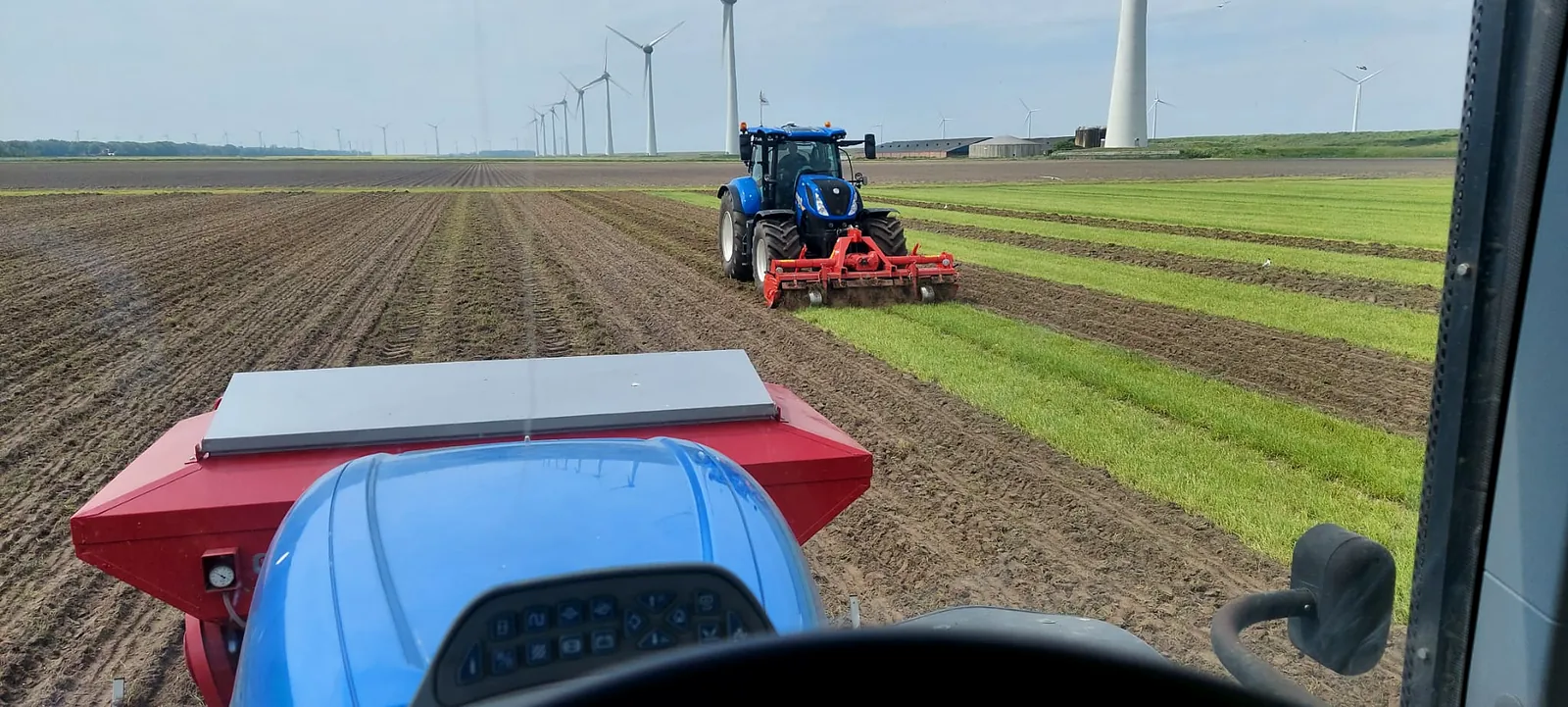 Trekker met kunstmesttank voorop en de spitmachine achterop tijdens het zaaien